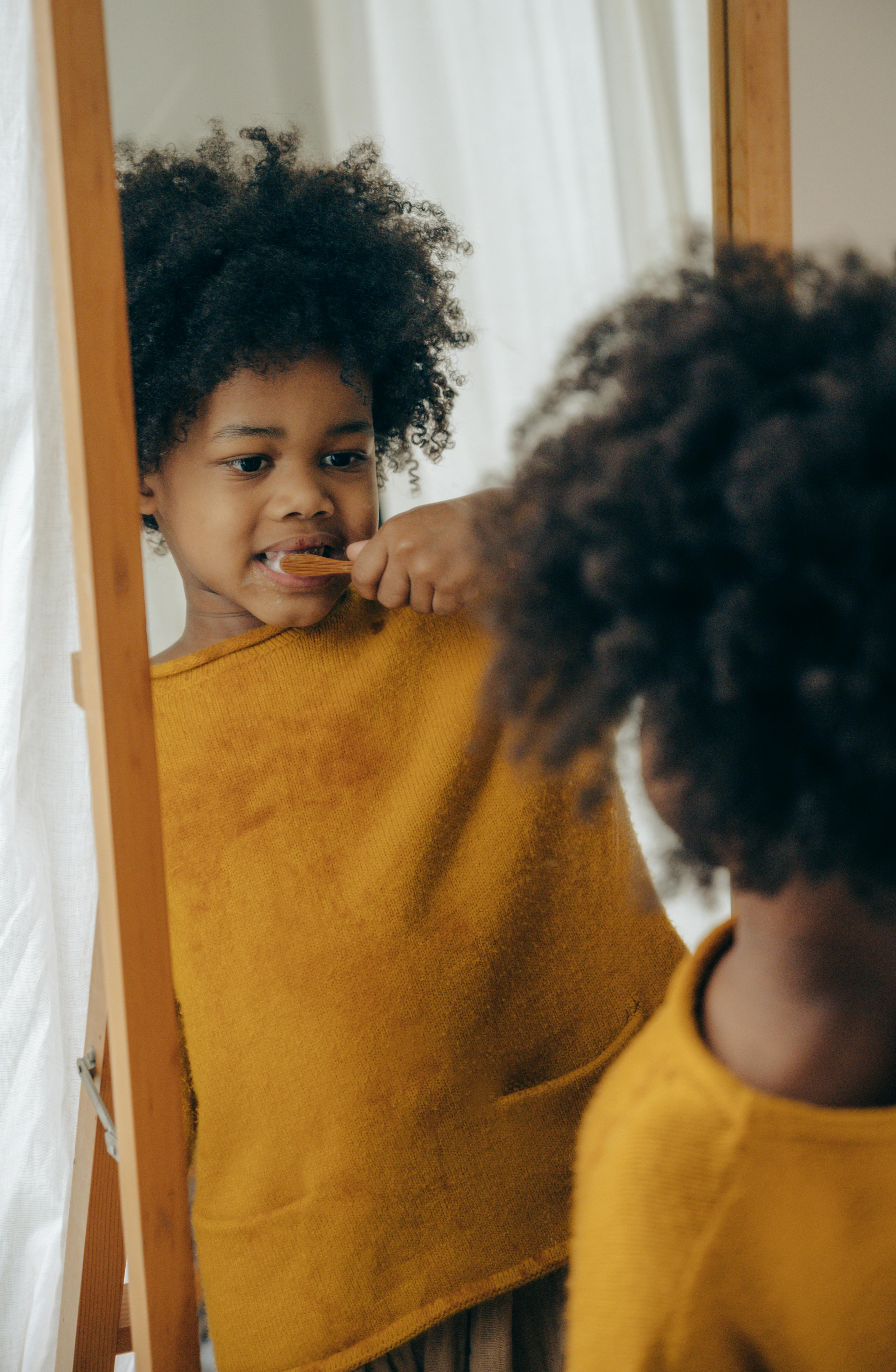 cute boy brushing teeth against mirror