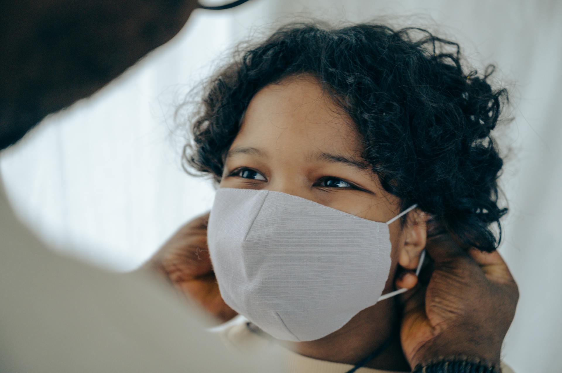 African American man helping positive little son to put protective face mask on during coronavirus outbreak