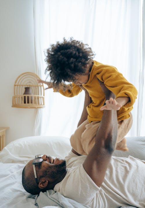 Excited father playing with son on bed