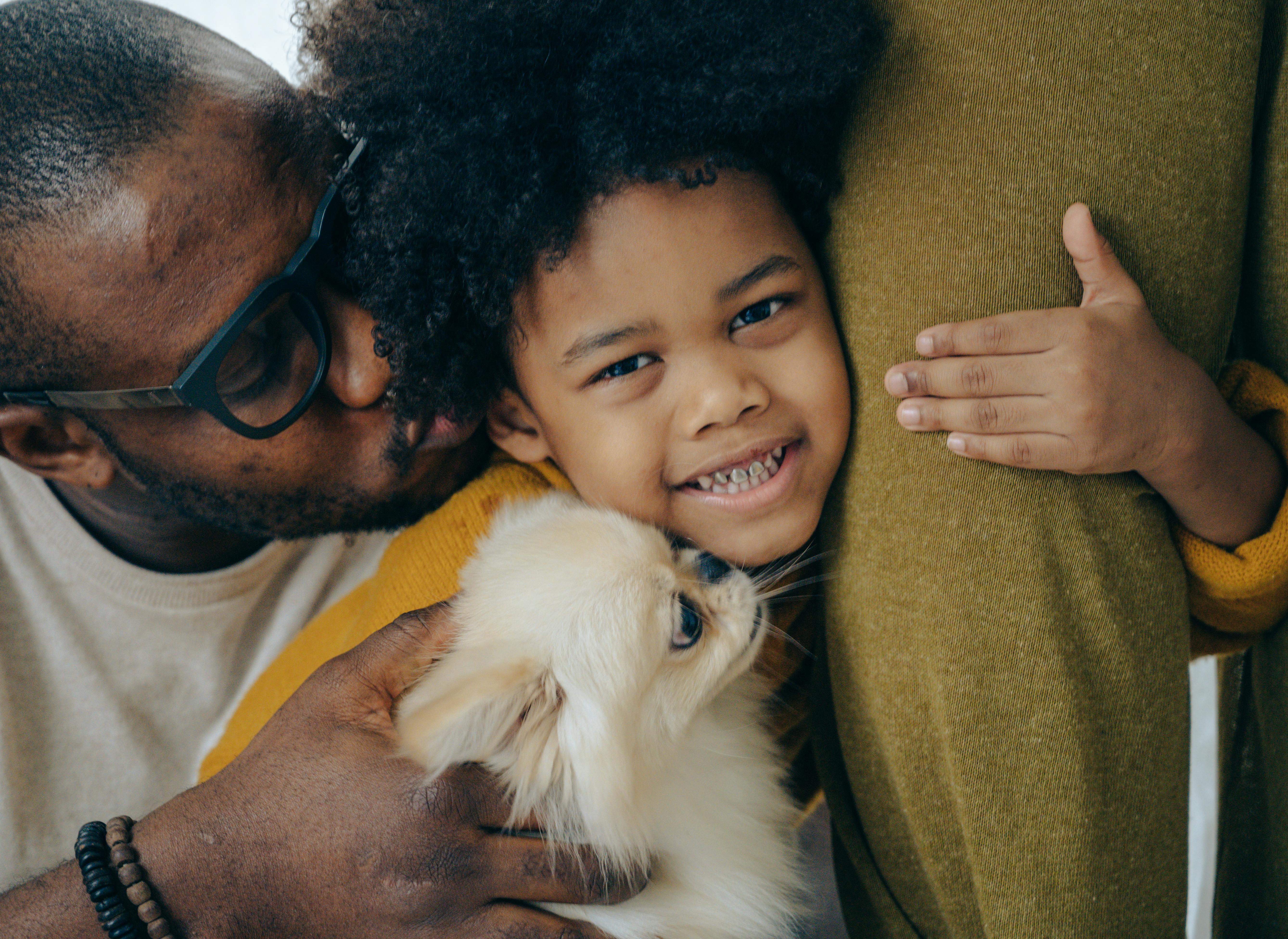 father hugging and kissing son with pekinese