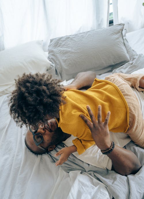 Free Happy father hugging and playing with son on bed Stock Photo