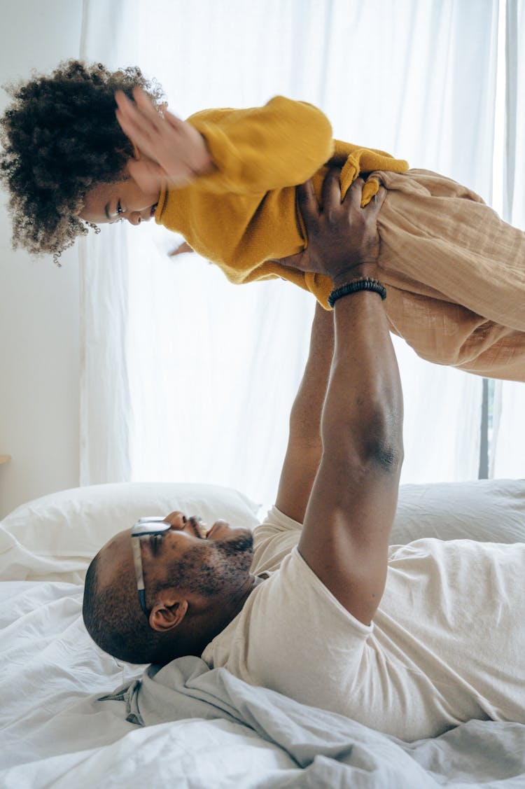 Father Playing With His Child In Bed