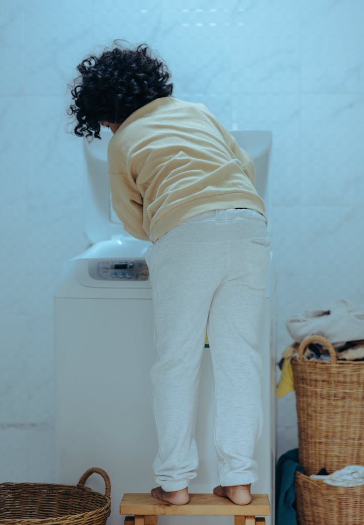 Child Loading Washing Machine In Laundry Room