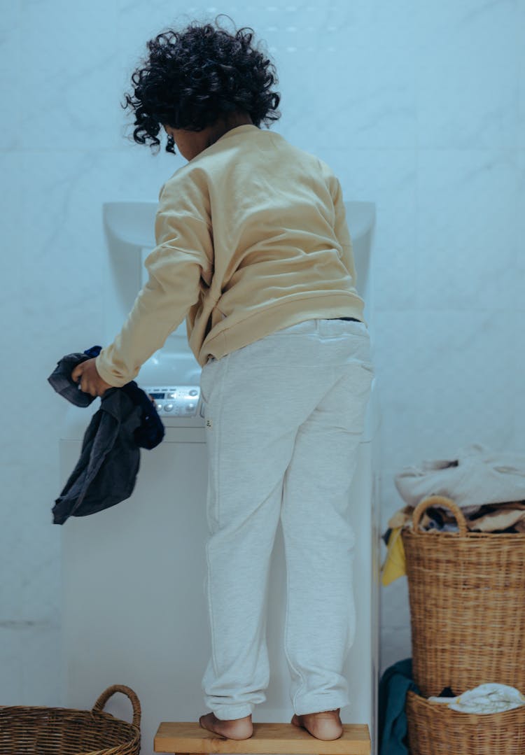 Confident Child Removing Clothes From Washing Machine