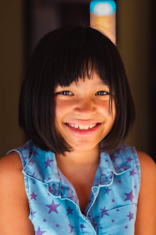 Happy ethnic child with toothy smile and dark hair sitting and looking at camera