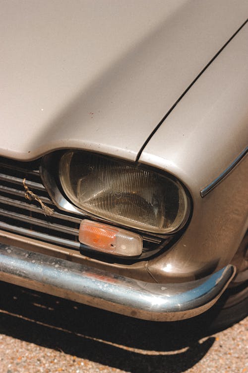 Headlight of old fashioned automobile parked on paved road on street in sunny day