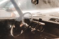Through glass of steering wheel of retro fashioned car parked on street in sunny day