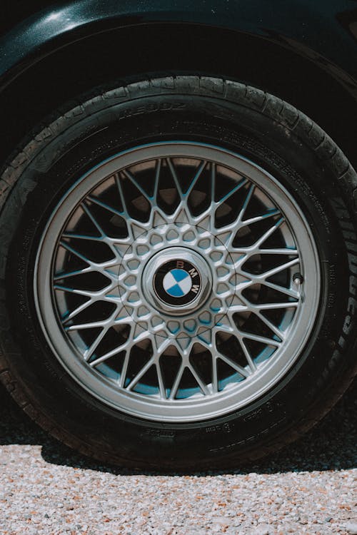Contemporary design automobile wheel tire with symmetrical metal spokes on rim on shabby roadway