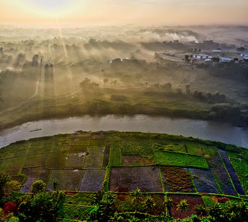 Free Aerial shot of lush agricultural fields in Gunung Sindur, Indonesia at sunrise with misty background. Stock Photo