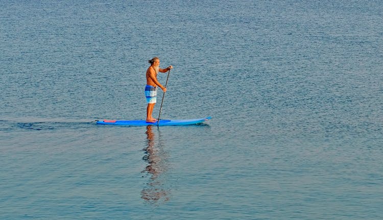 Unrecognizable Senior Man On Sup Board On Sea