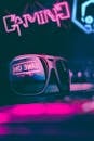 Trendy sunglasses reflecting neon light sign in dark room