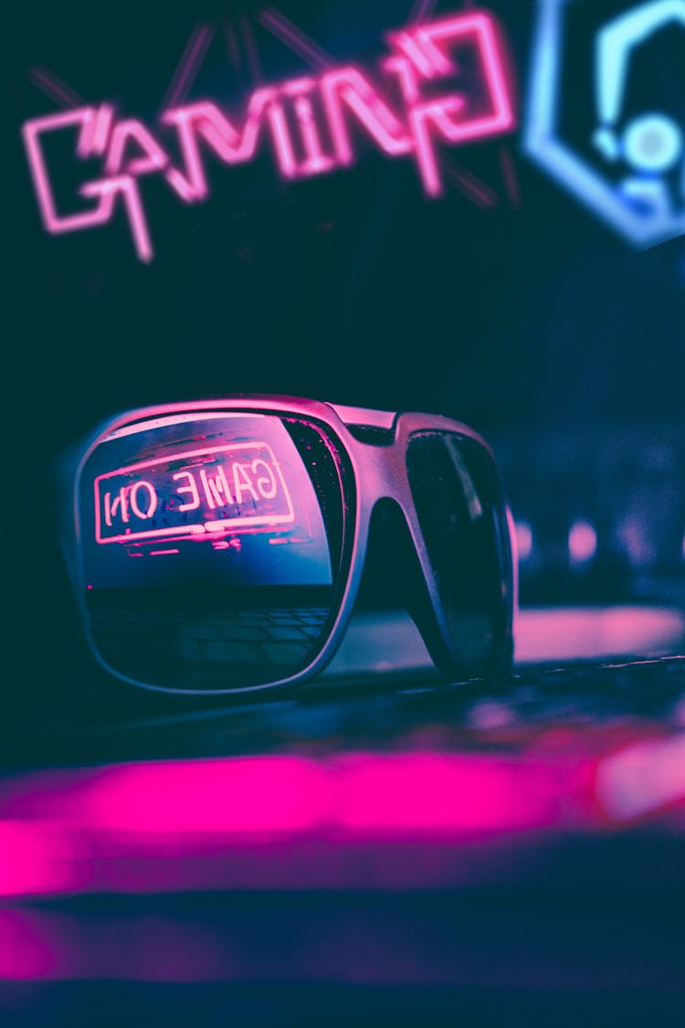 Trendy Sunglasses Reflecting Neon Light Sign In Dark Room