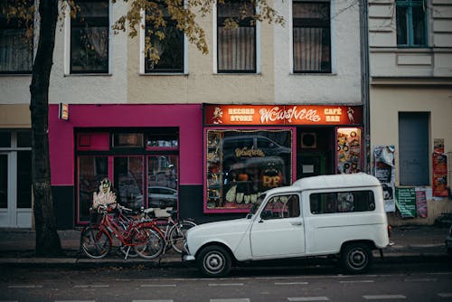 White 5 Door Hatchback Parked Beside Red and Black Bicycles