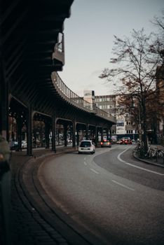 城市街道场景显示，弯曲道路上的车辆正行驶在夜晚的高架铁路下