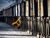 Yellow plastic chair hanging on fenced wall on ancient cobblestone market square on sunny day