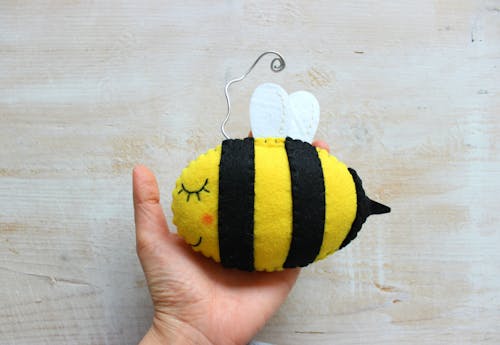 Free A Hand Holding a Handmade Bee Stuffed Toy Stock Photo