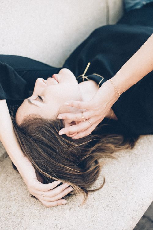 Free A serene woman in a black dress poses resting on a couch with her eyes closed, exuding calmness. Stock Photo