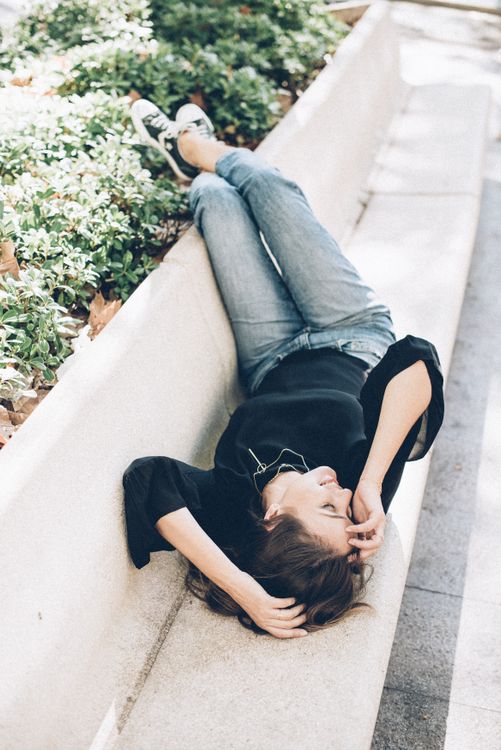 A Woman Lying Down on a Concrete Bench · Free Stock Photo