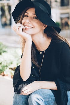 一位戴着黑色帽子和衬衫的迷人女性在户外微笑，尽显休闲优雅