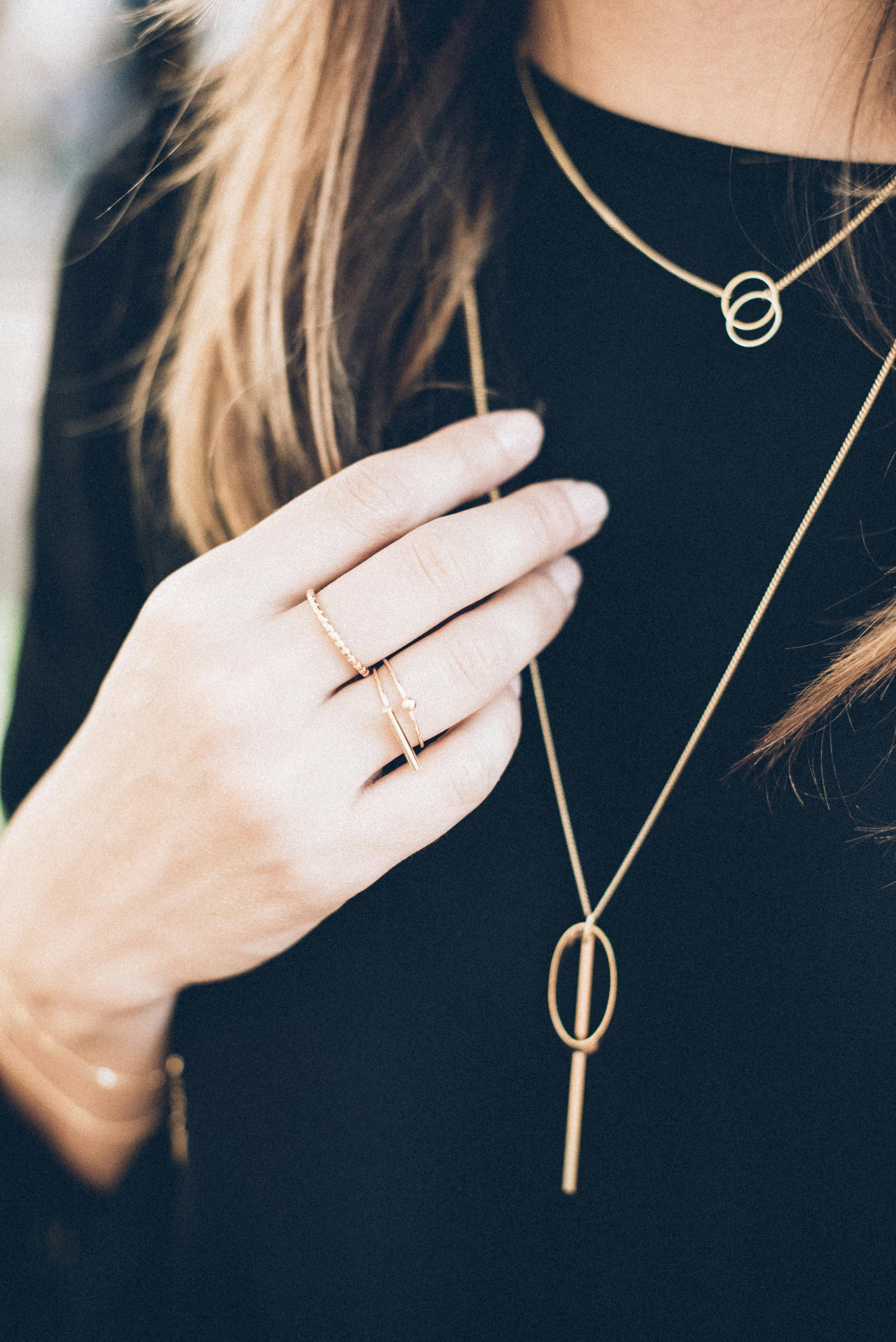 a woman wearing a gold necklace and gold rings