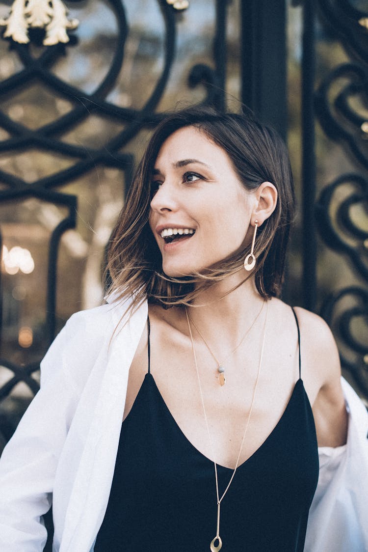 A Happy Woman Wearing Gold Earring And Necklace While Looking Afar