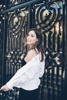 一位身着黑色连衣裙的时尚女子，在华丽的大门前优雅摆姿，散发着迷人魅力