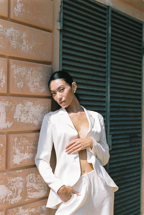 Femme En Blazer Blanc Debout à Côté Du Mur De Briques