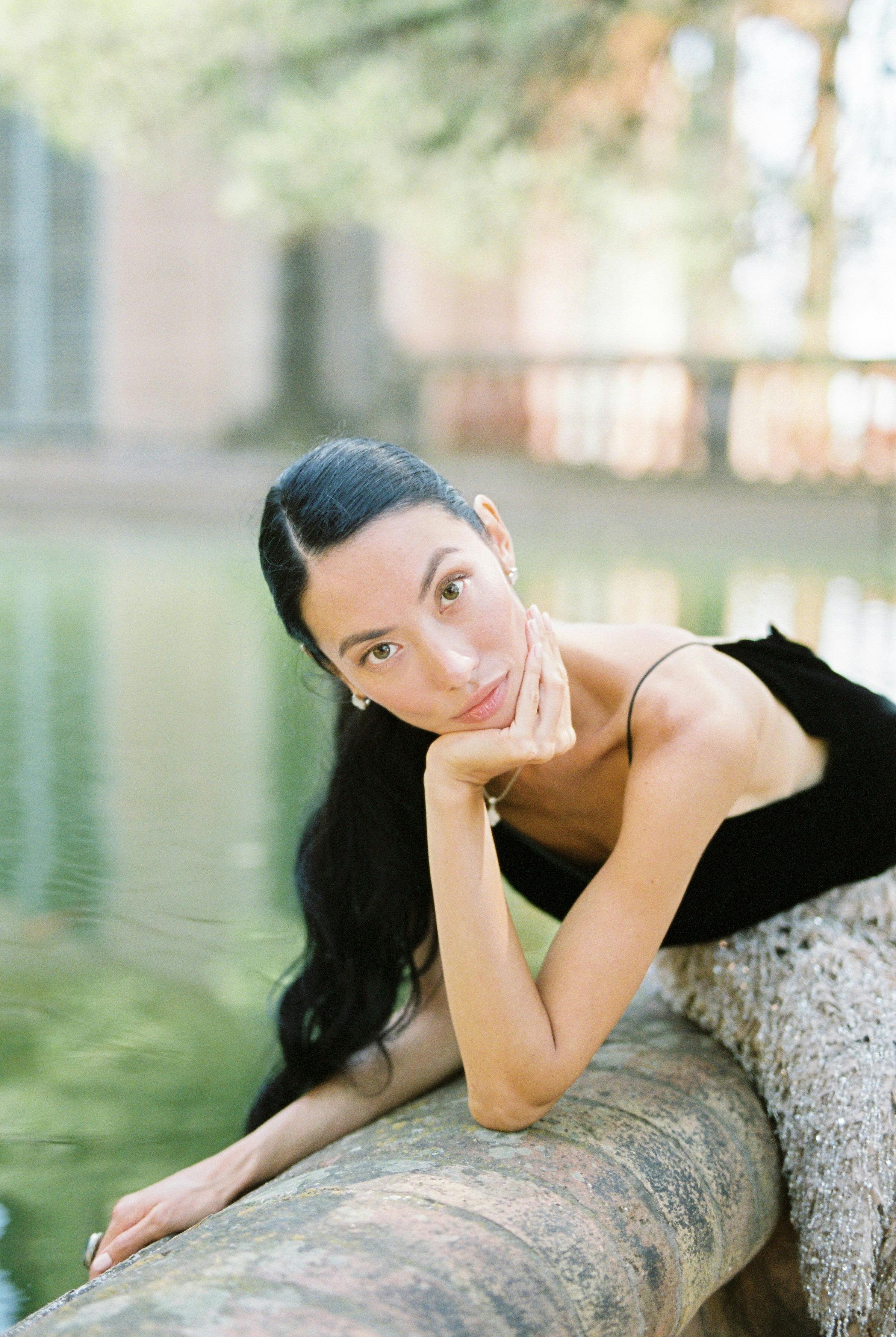 一位时尚女士优雅地在宁静的户外反光池旁摆姿势