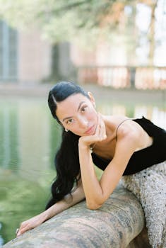 一位时尚女士优雅地在宁静的户外反光池旁摆姿势