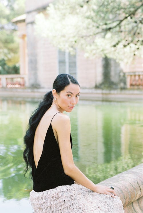 A Woman in Black Tank Top Sitting Near the Body of Water