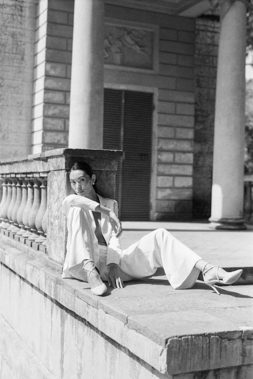 Woman in White Coat and Black Hat Sitting on Concrete Bench