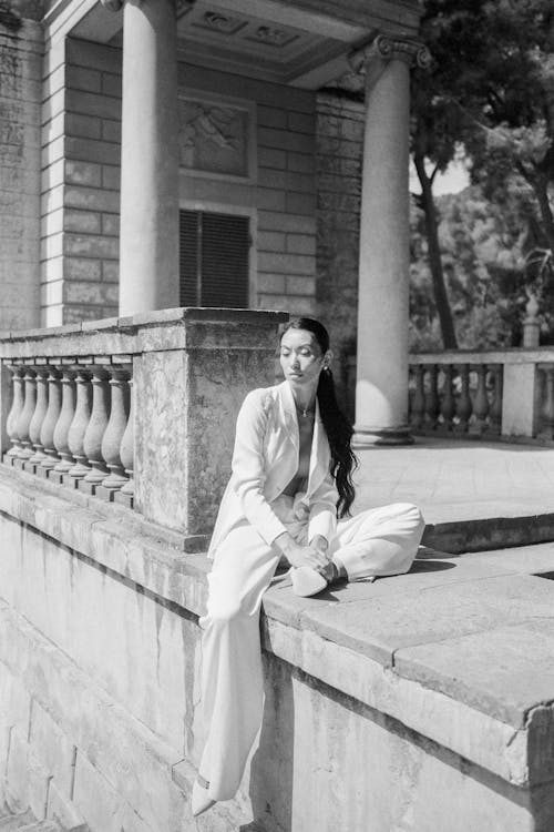 Woman Sitting on Concrete Pavement Near Railings