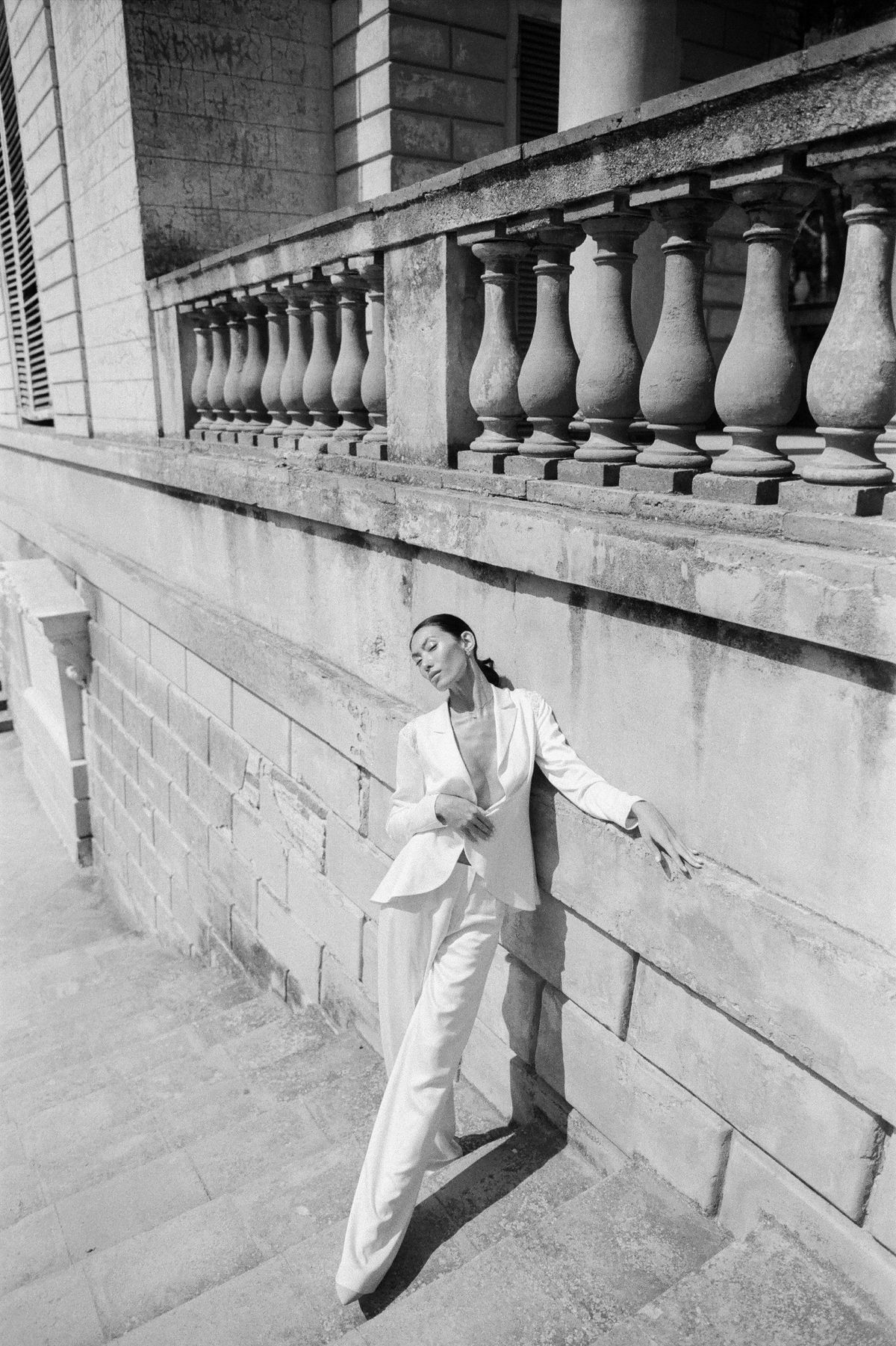 A woman in a white jacket and trousers on steps — tonal summer tailoring head to toe