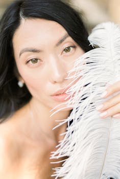 Close-up of a woman with a soft focus feather, highlighting serenity and elegance.