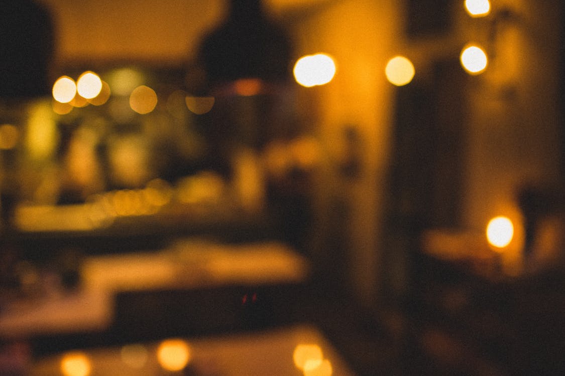Defocused interior of restaurant illuminated with various bright lamps shining with warm lights in evening