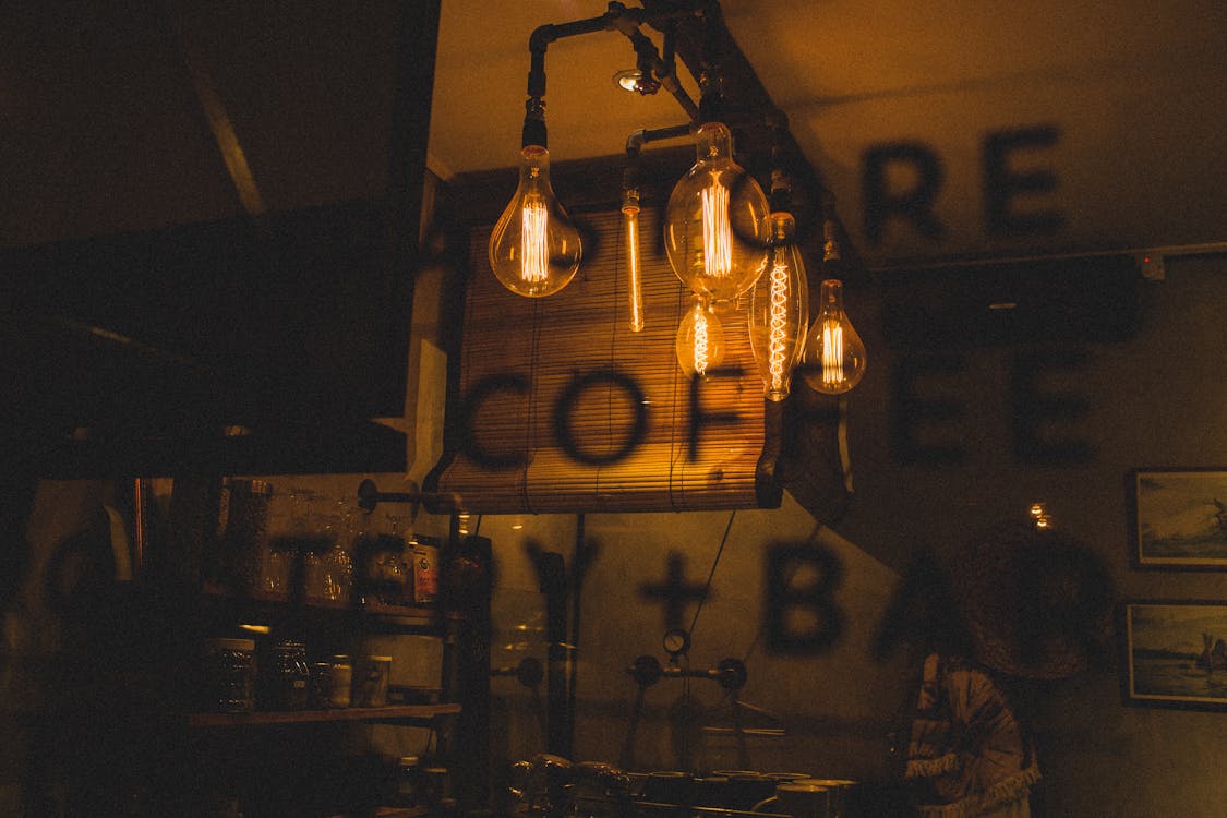 Through bar window view of glowing light bulbs in dark interior with cafeteria information on glass