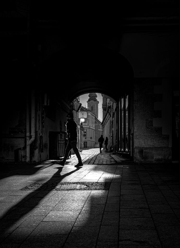 Unrecognizable Person Walking Along Street Near Arched Passage In Old City