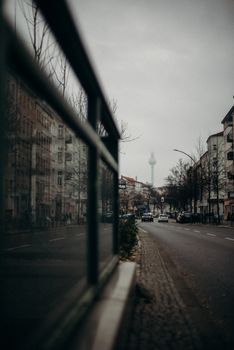 Moody urban street view in Berlin featuring a distant TV tower under overcast skies.