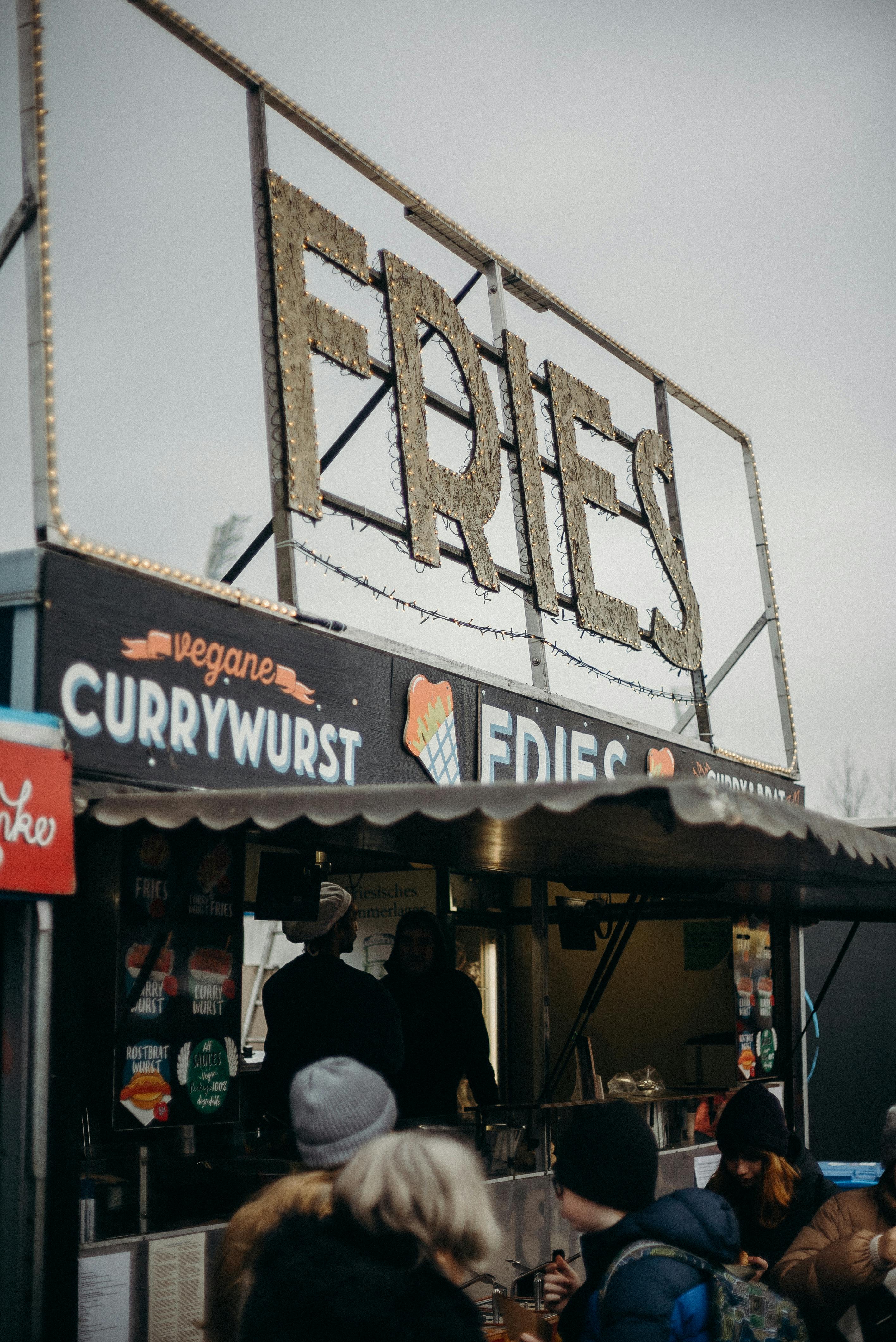 Free Outdoor street food stall offering fries and vegan currywurst at a market. Stock Photo