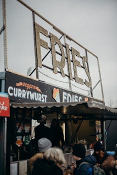 Outdoor street food stall offering fries and vegan currywurst at a market.