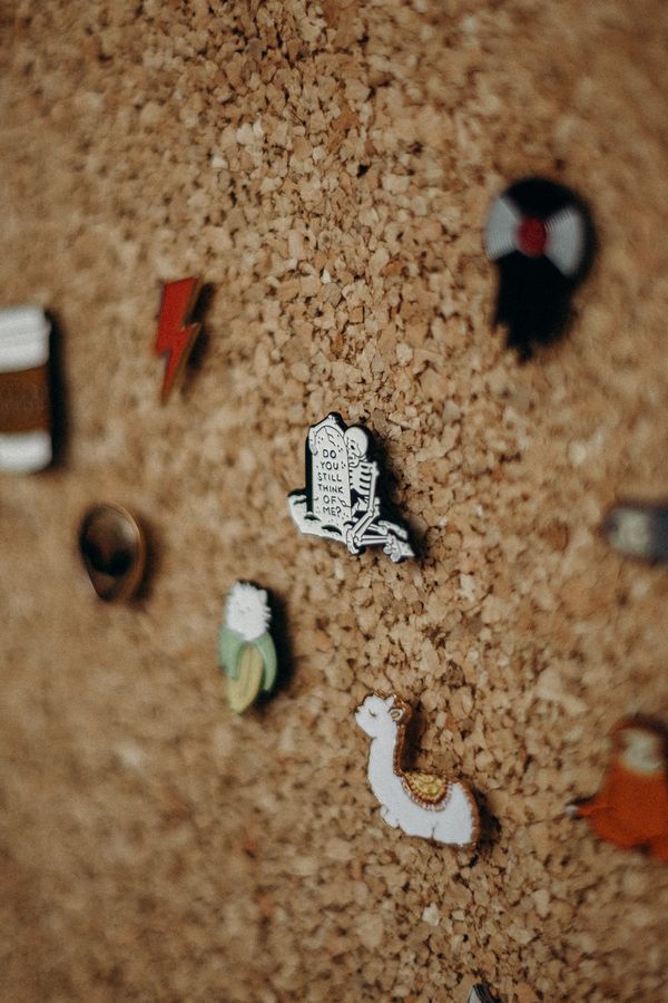 Collection of enamel pins on a cork board — photo by cottonbro studio on Pexels