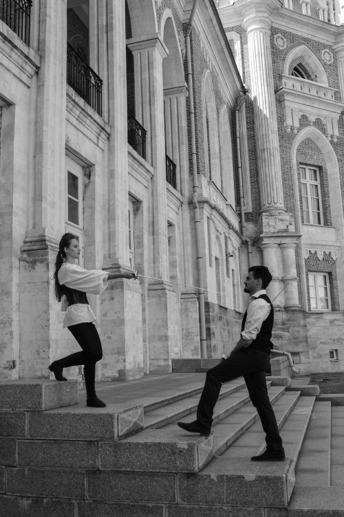 Free Side view of black and white young man and woman in similar clothes standing on stairs of historical building and looking at each other Stock Photo