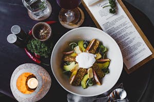 Delicious avocado salad with sauce and menu aside in restaurant
