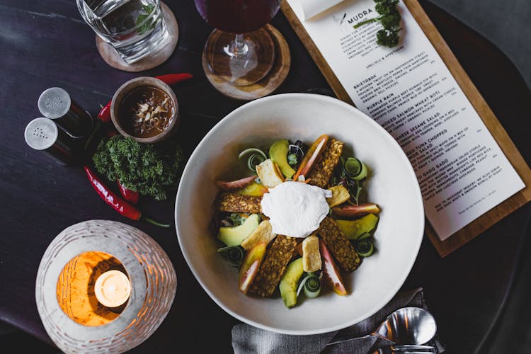 Delicious Avocado Salad With Sauce And Menu Aside In Restaurant