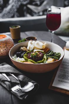 From above of appetizing plate with green beans and batata pieces and different types cabbage and squid pieces with avocado slices and red rice in middle of oriental dish served with glass of drink on table of restaurant - Fotografer Sidoarjo