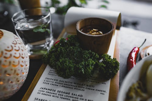 Free High angle table with bunch of fresh green curly parsley placed on menu with sauce cup near glass of water Stock Photo