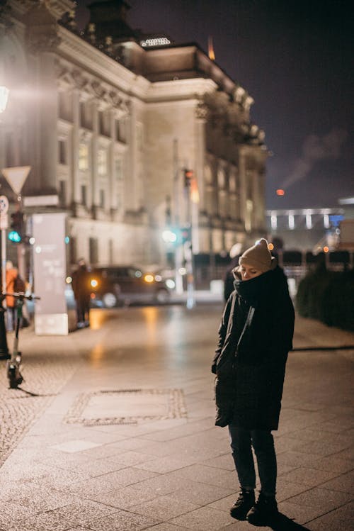 Person in Black Coat Walking on Sidewalk during Night Time