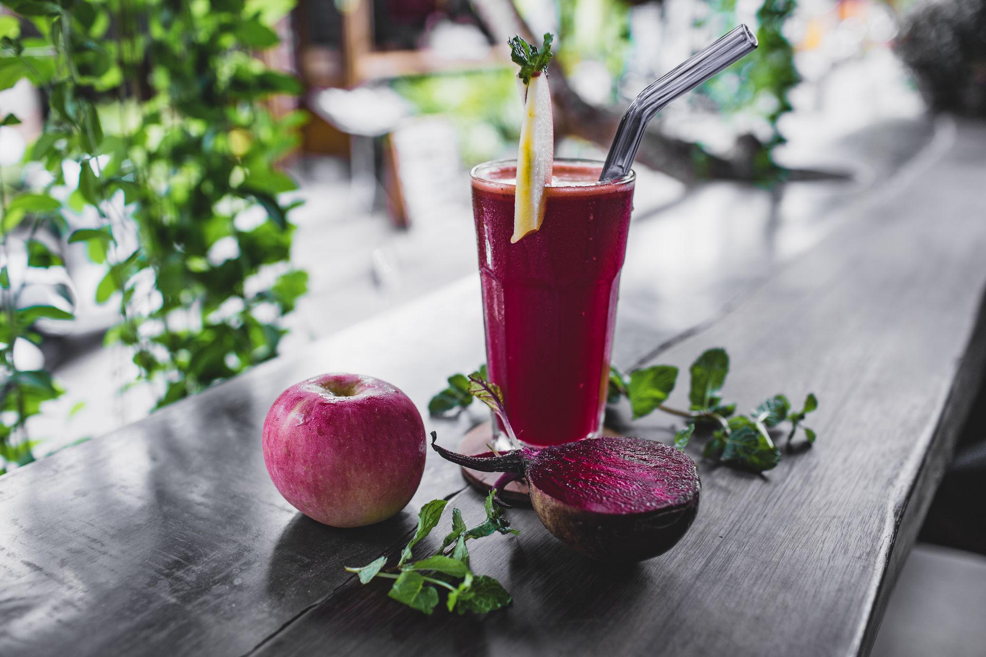 A glass of fresh beetroot juice and beetroots on a table.