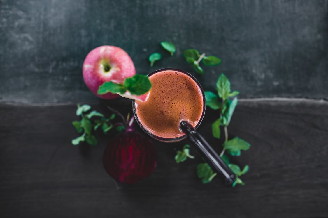 Detox juice served on black table with apple and beetroot