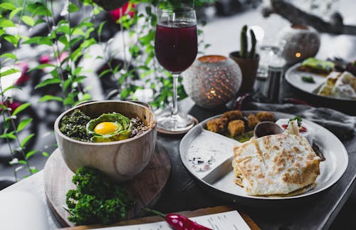 High angle of beautiful served table in outdoor cafe with various exotic dishes in bowl and plates